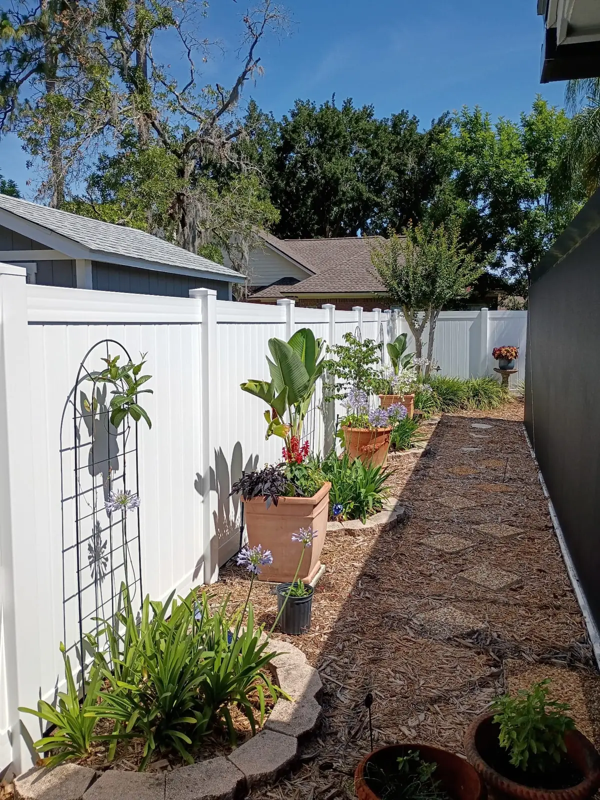 White vinyl privacy fence bordering a landscaped residential side yard