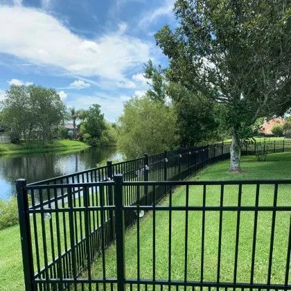 Black aluminum fence keeping an open view across a neighborhood pond