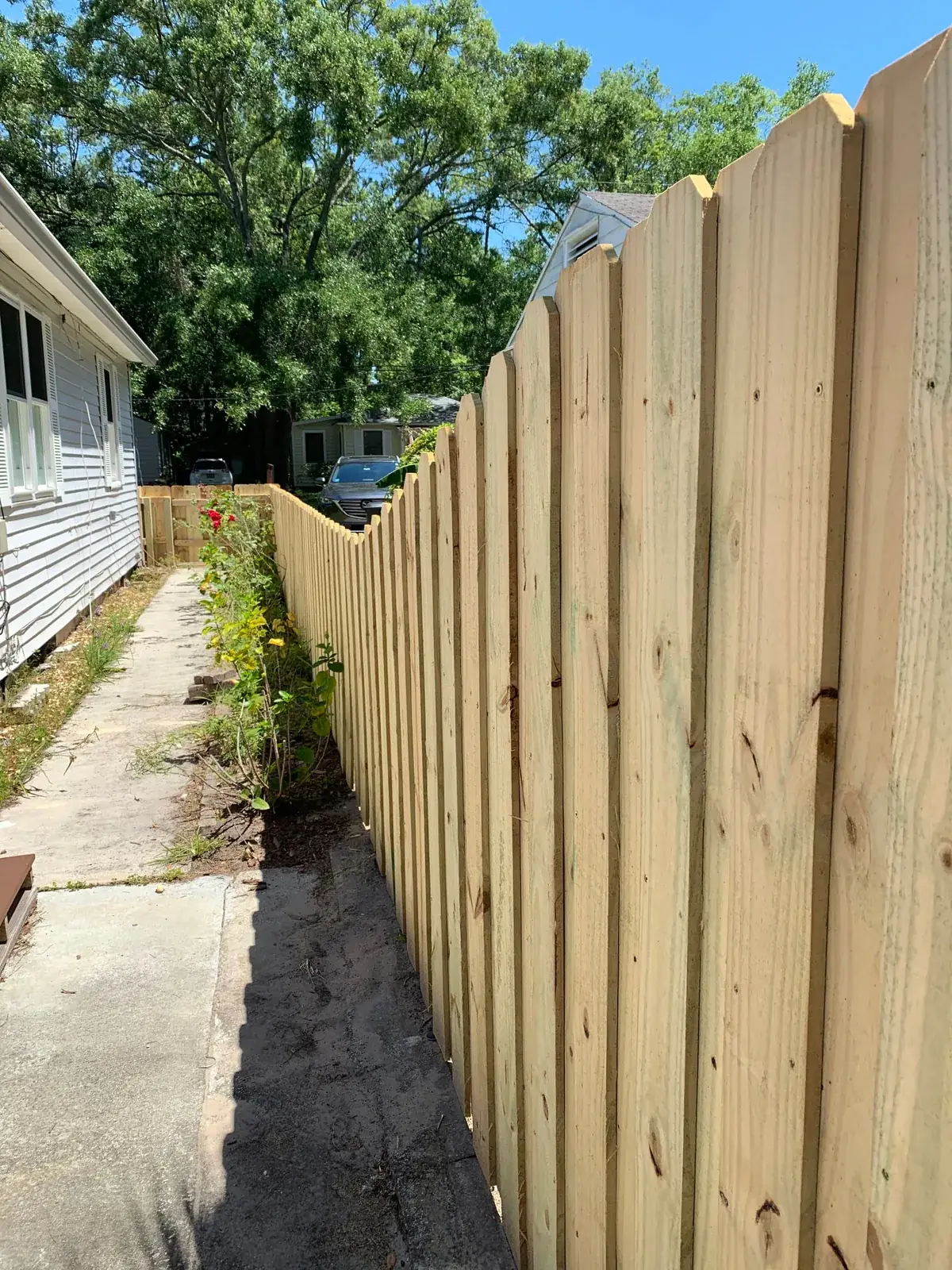 Wood privacy fence along a narrow concrete side yard between two homes
