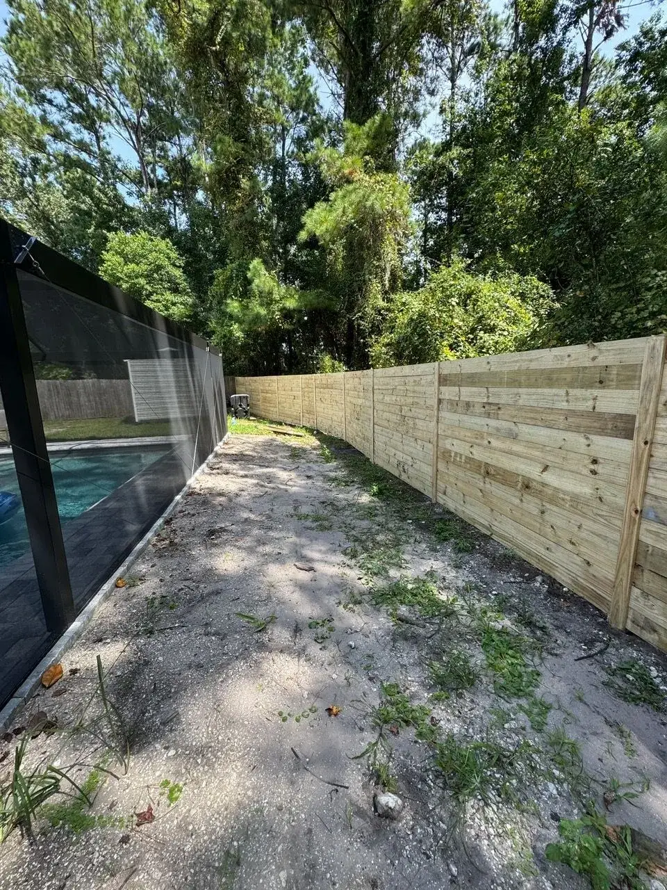 Wood fence enclosing the walkway beside a screened pool enclosure