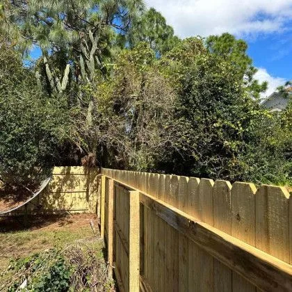 Wood privacy fence installed at the tree line of a heavily wooded back yard