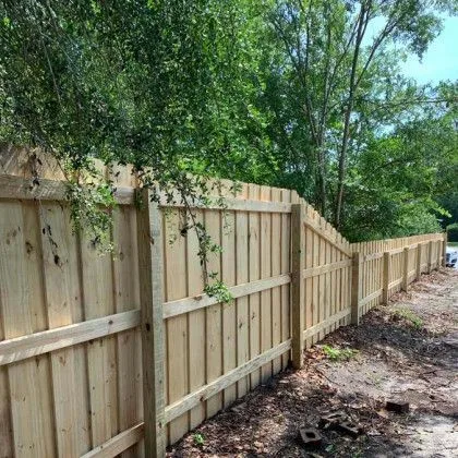 Wood fence with a picket top detail bordering a wooded residential lot