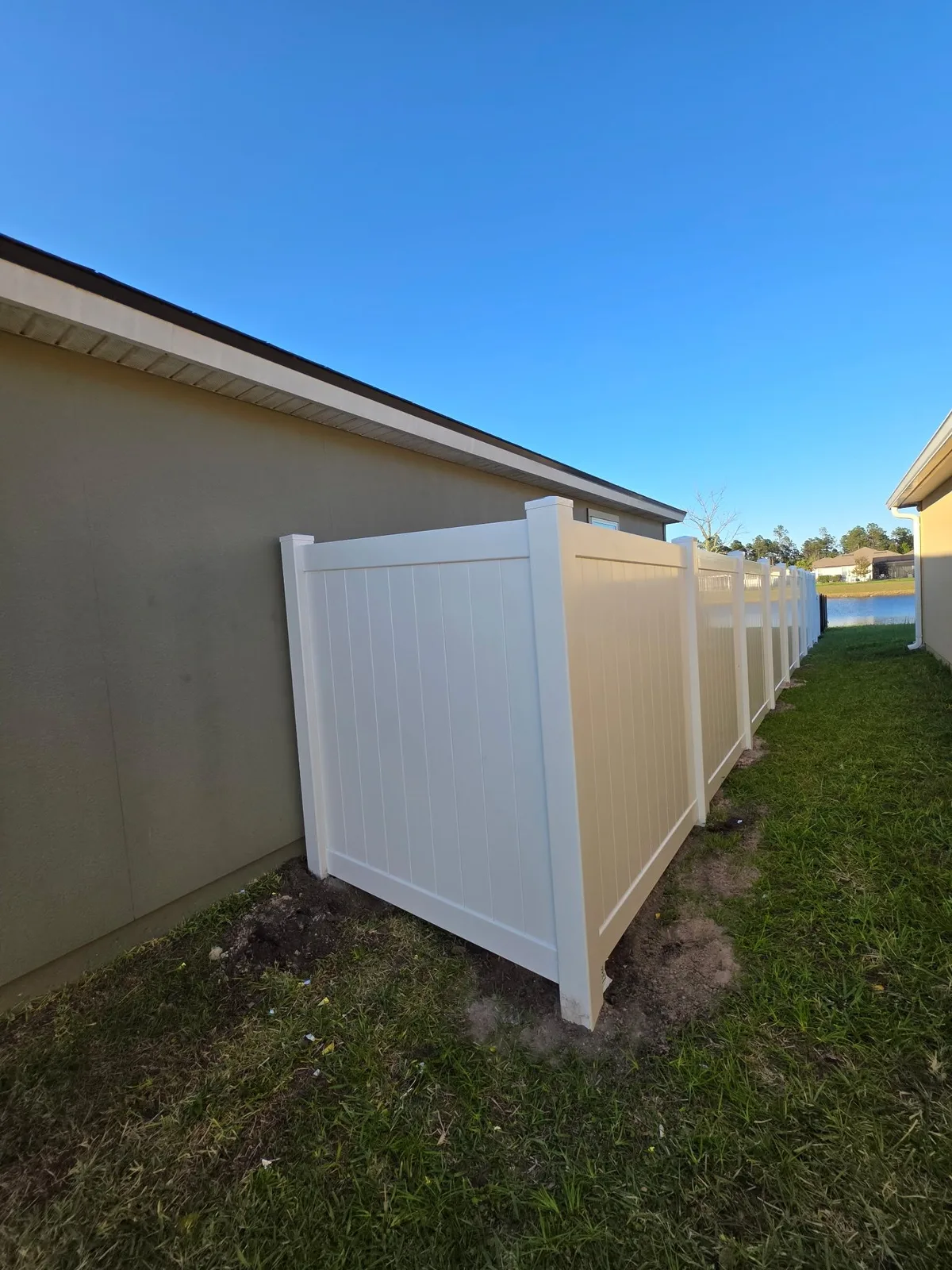 White vinyl fence and gate closing a narrow side yard between homes