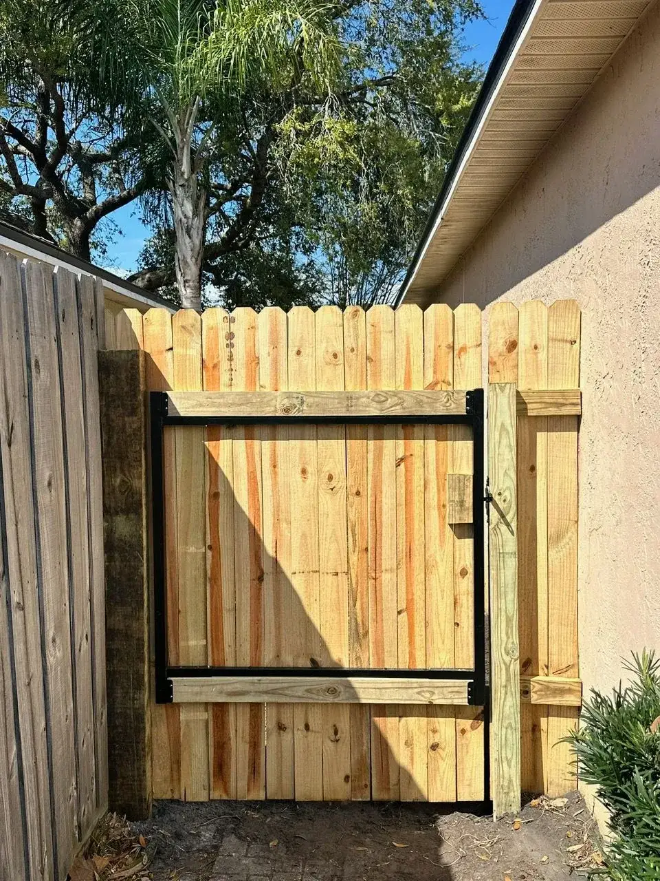 Wood walk gate built on a welded steel frame beside a home